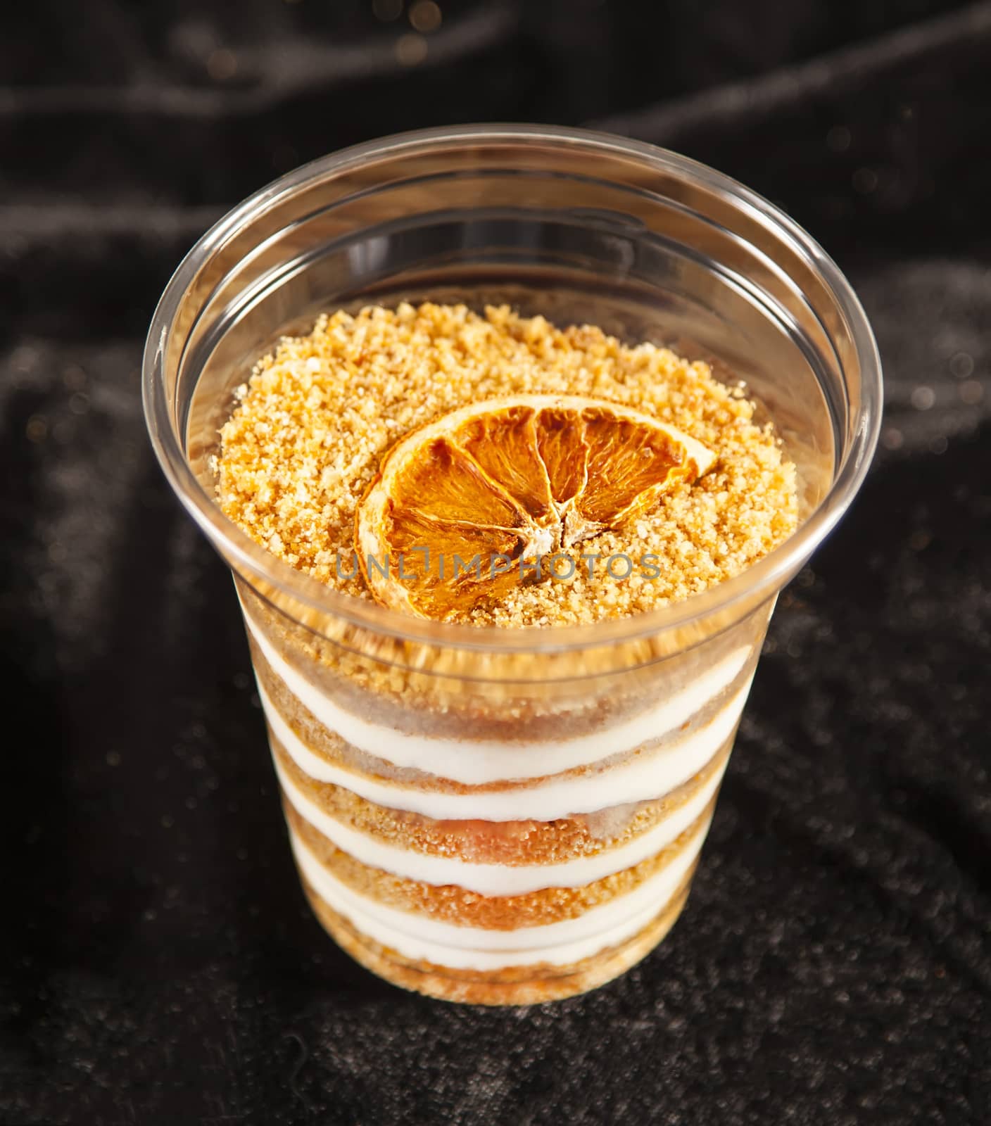 Honey cake in plastic cup on black background by RawGroup