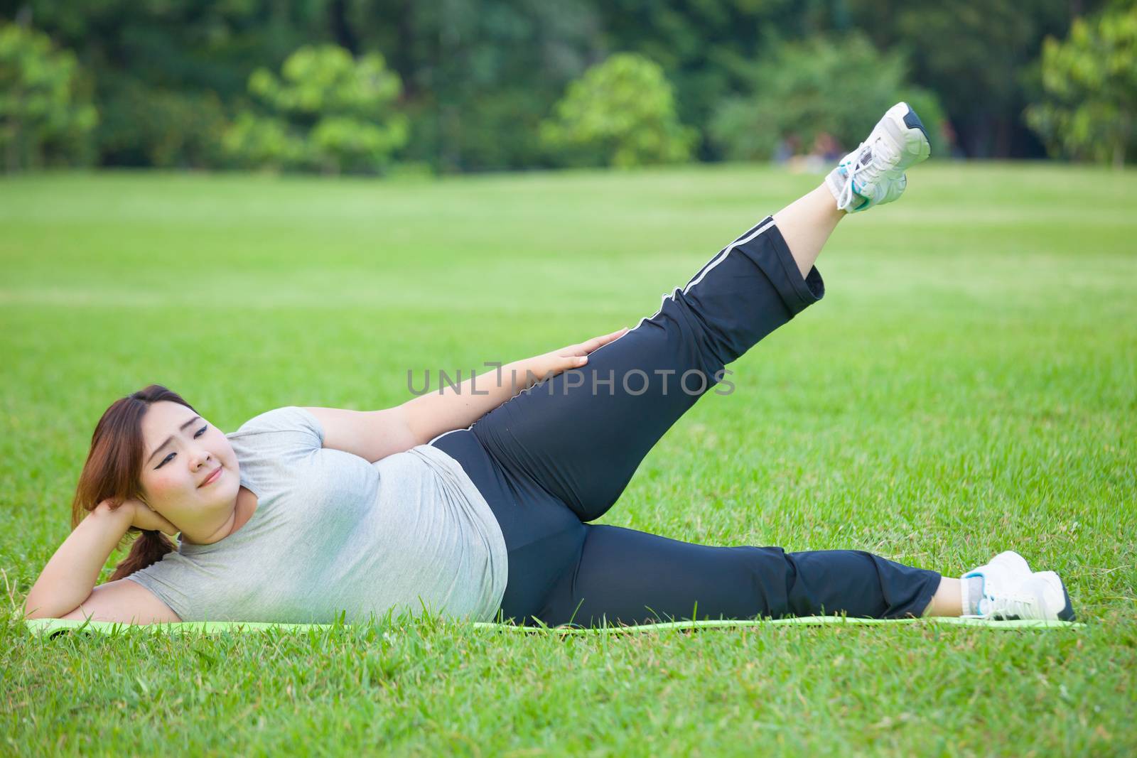 Asian fat woman lying by exercise leg upwards at the park