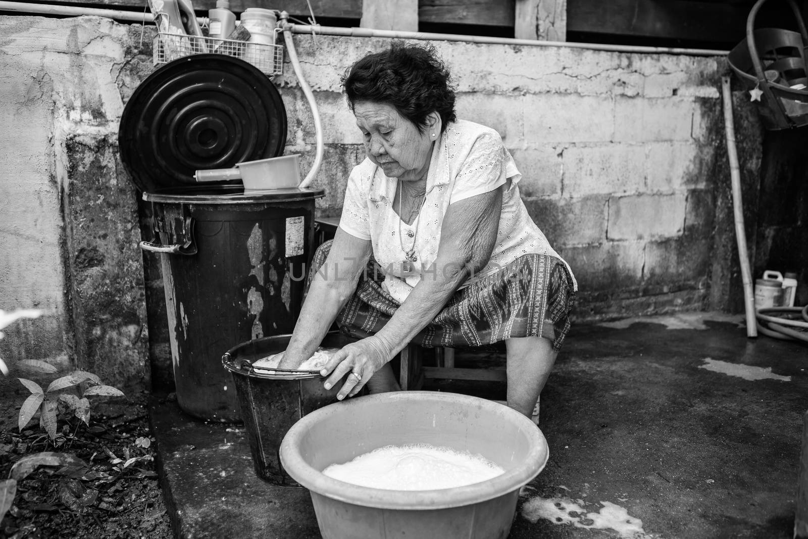 Senior asian woman washing cloths by hand by witthaya