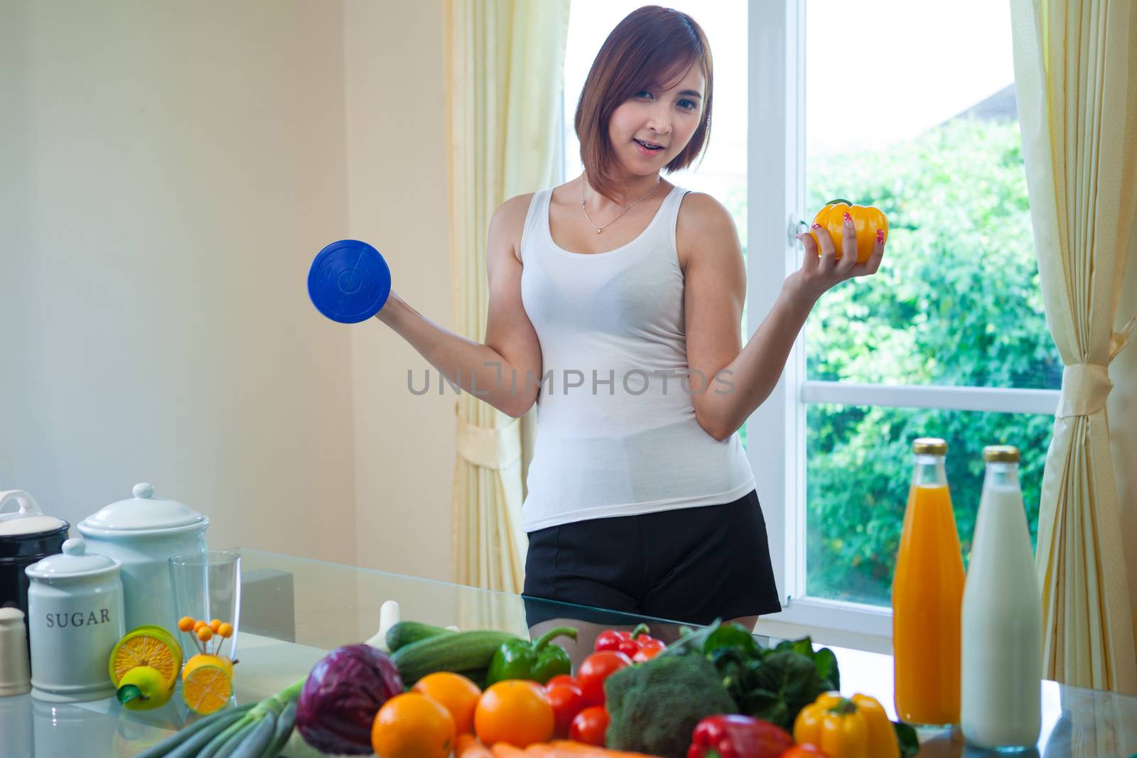 Portrait of a healthy asian woman with vegetables and dumbbell in home