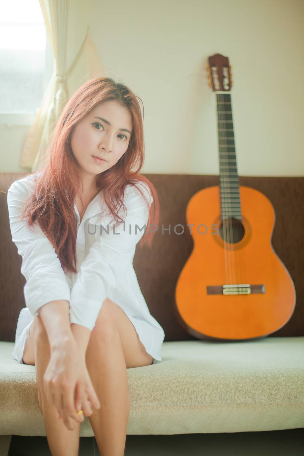 Young beautiful asian woman playing guitar in bed room