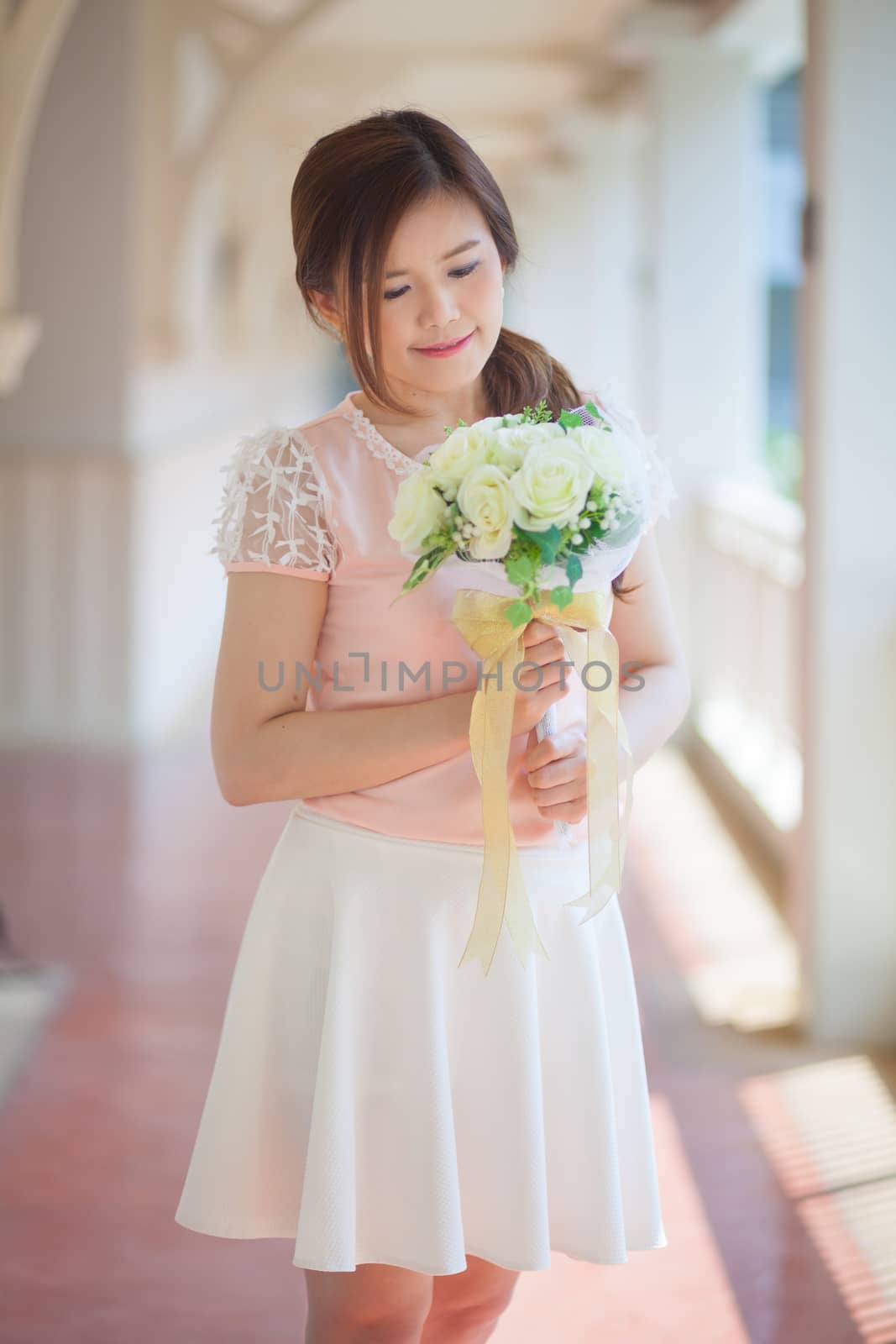 Young asian cute woman smelling white flowers by witthaya