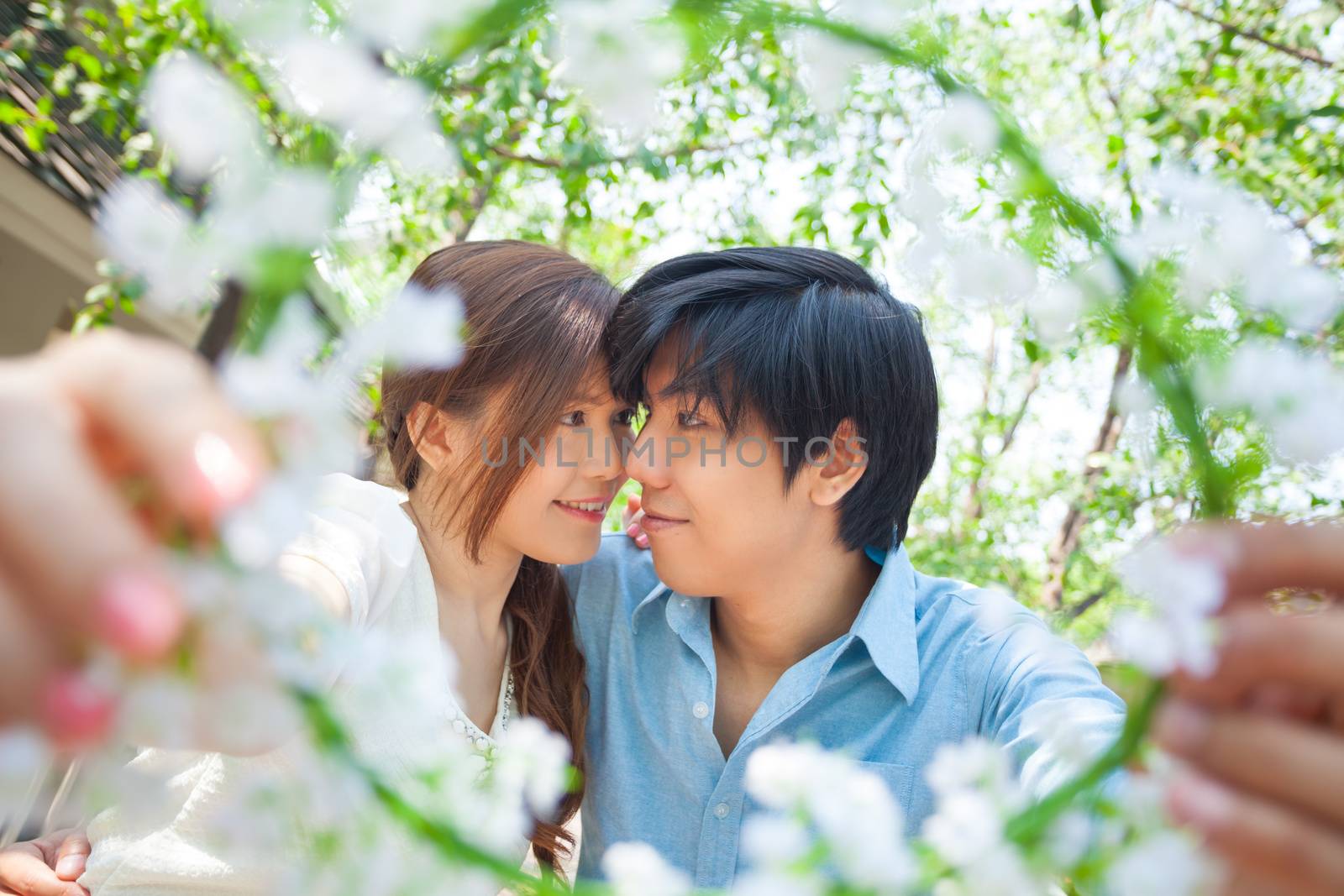 Loving asian couple under tree in the park by witthaya