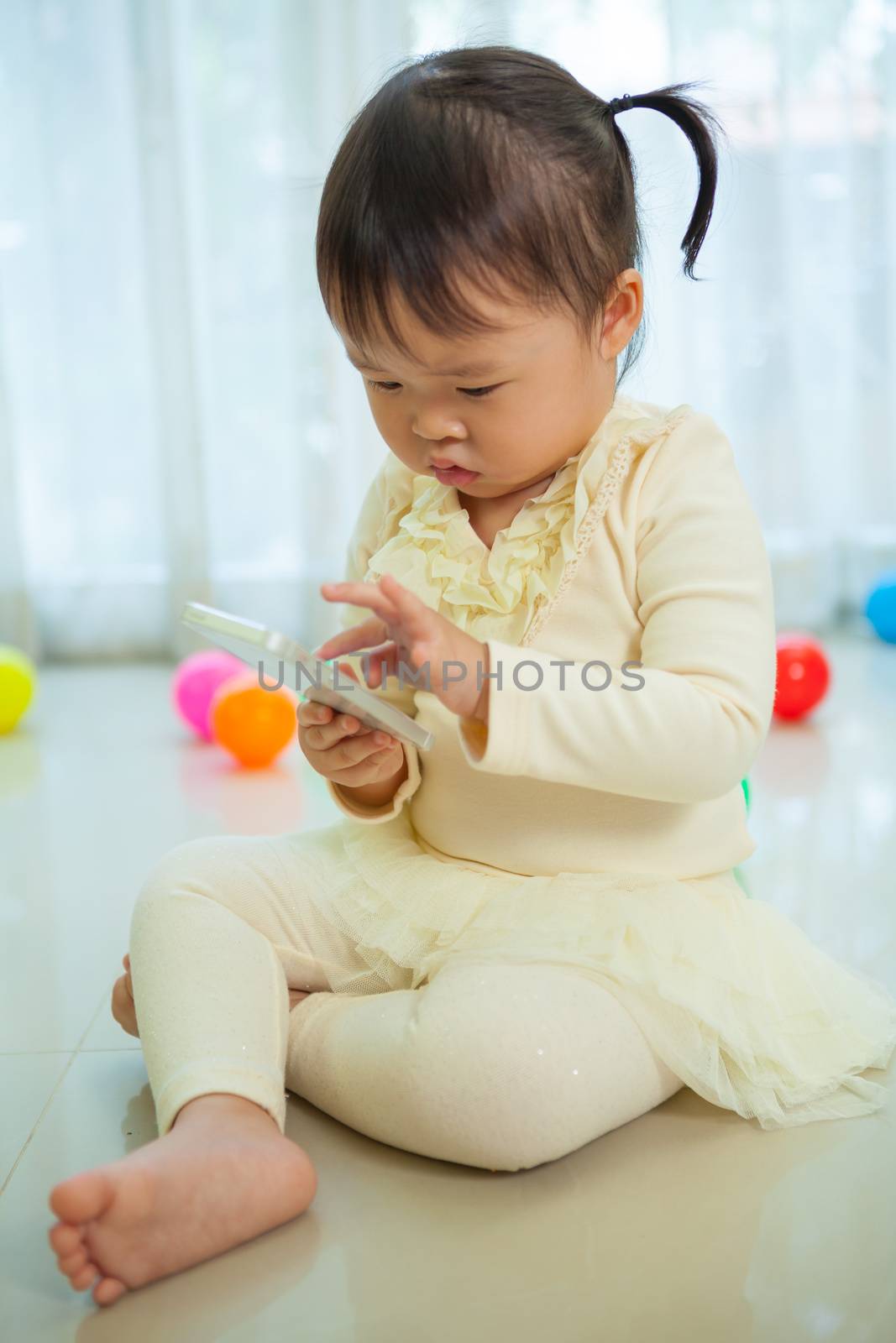 Happy little asian girl using mobile phone in the home