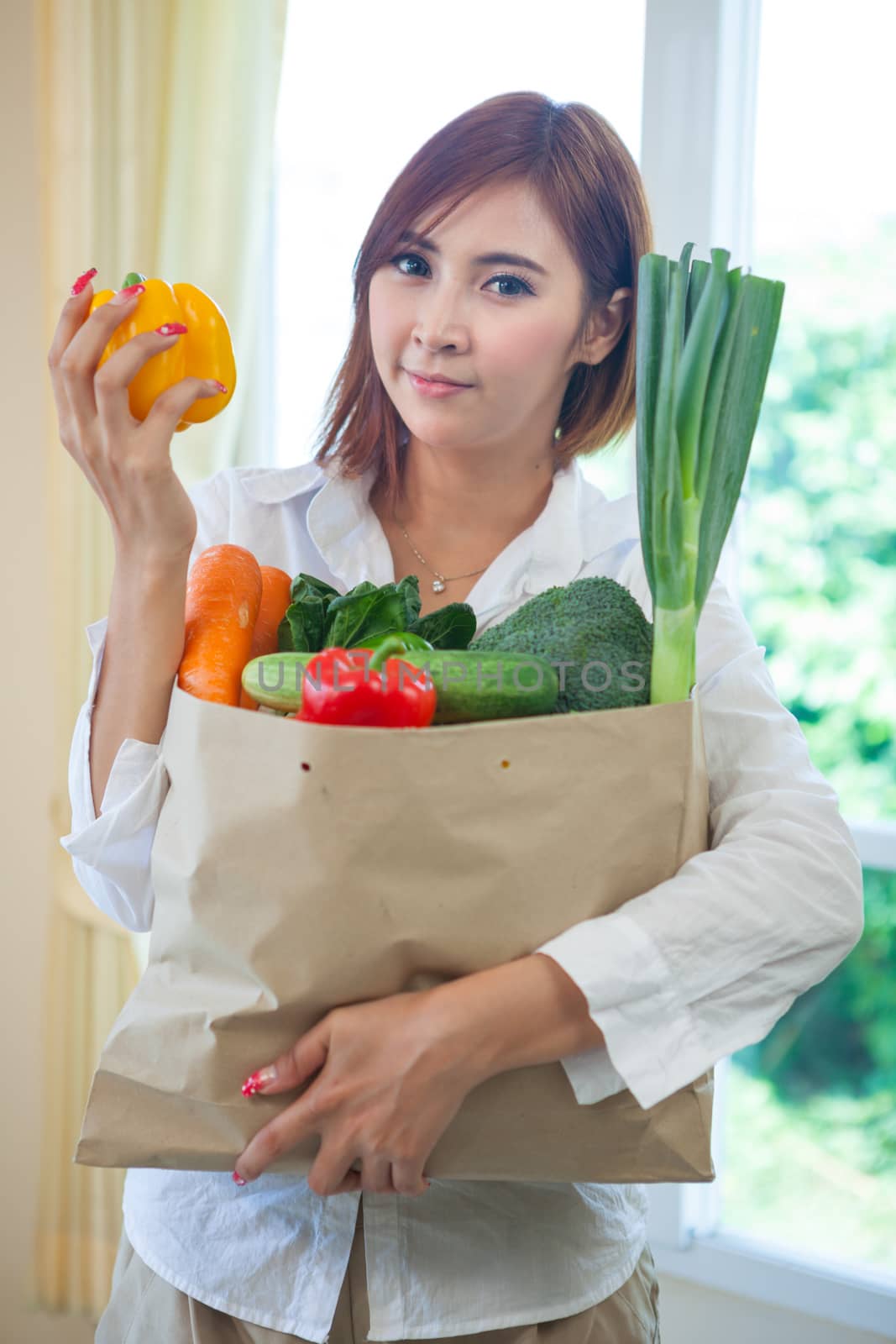 Happy asian woman cooking vegetables green salad in the kitchen