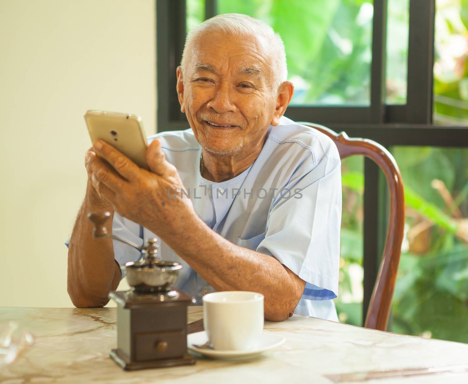 Happy asian senior man using the mobile phone in home