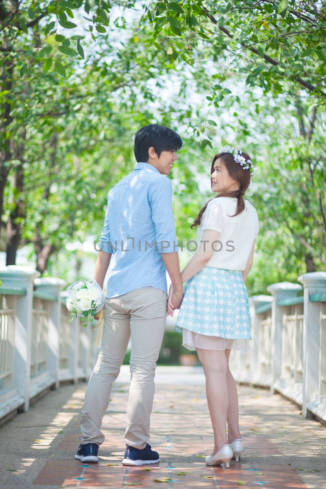 Loving asian couple under tree in the park by witthaya