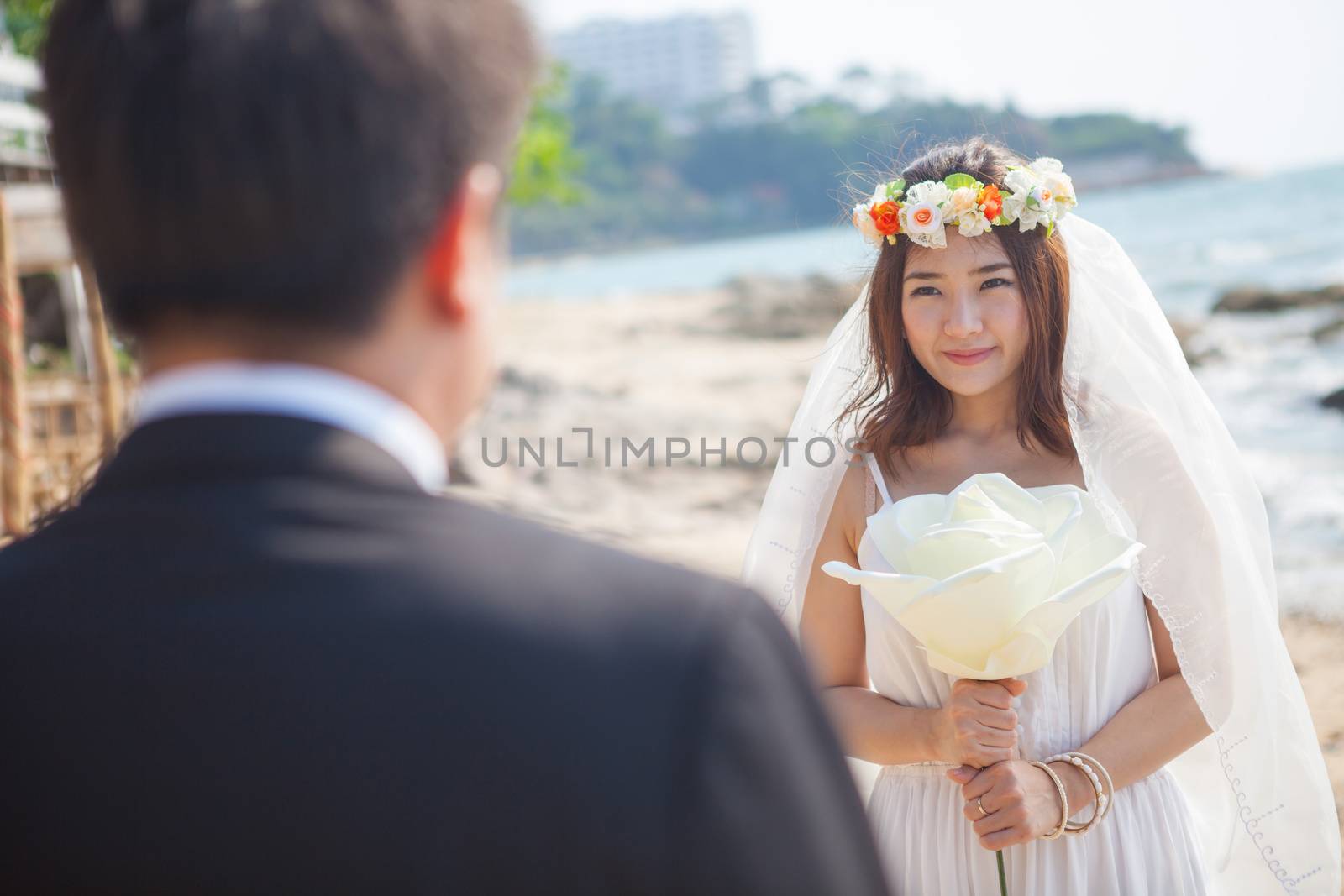 Beautiful asian couple on the beach in wedding dress