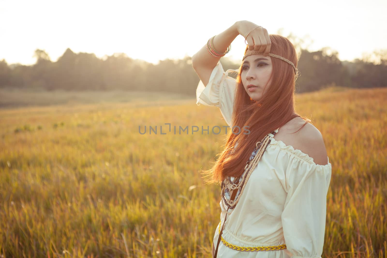 Hippie woman posing in golden field on sunset