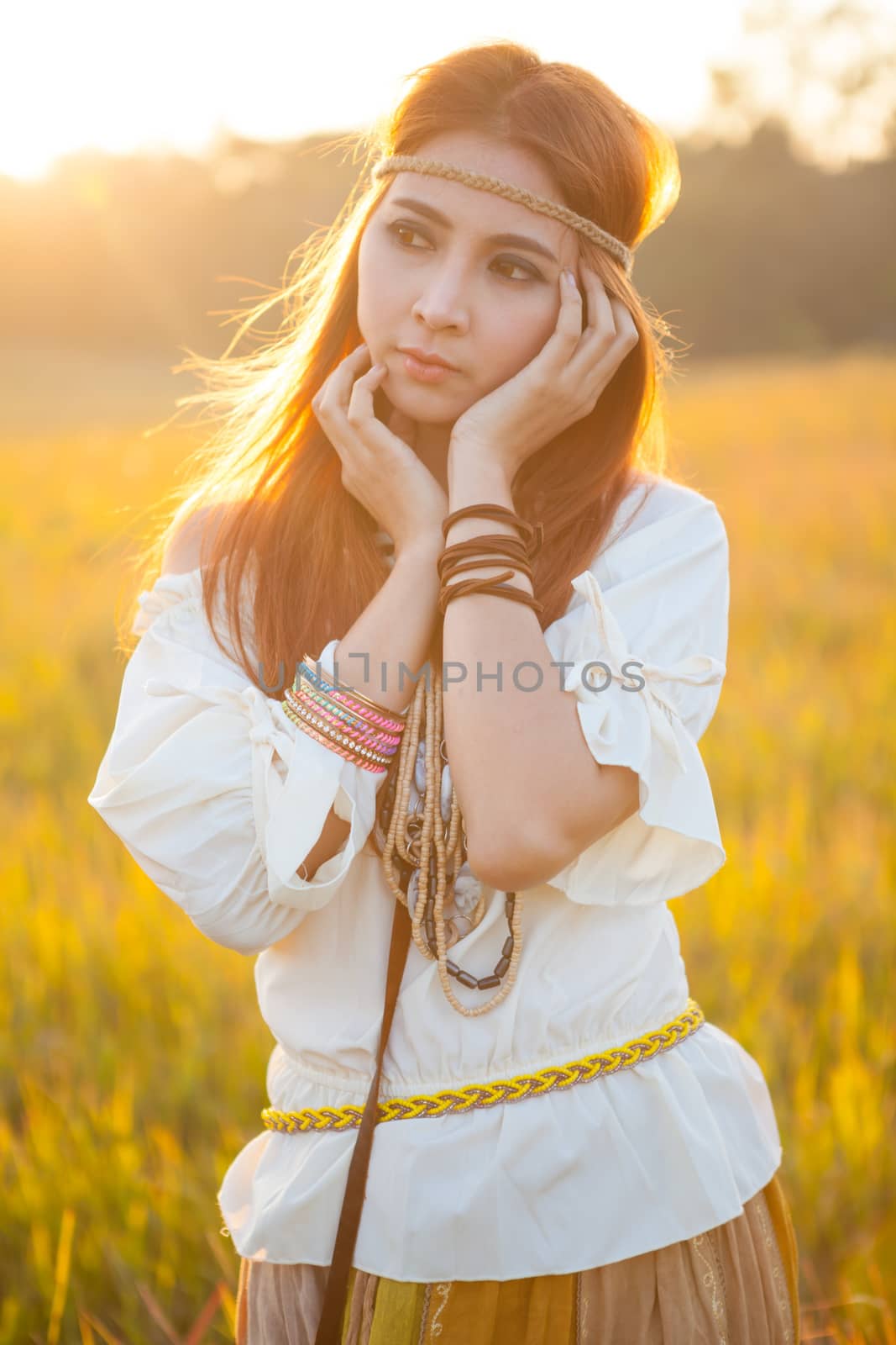 Hippie woman posing in golden field on sunset