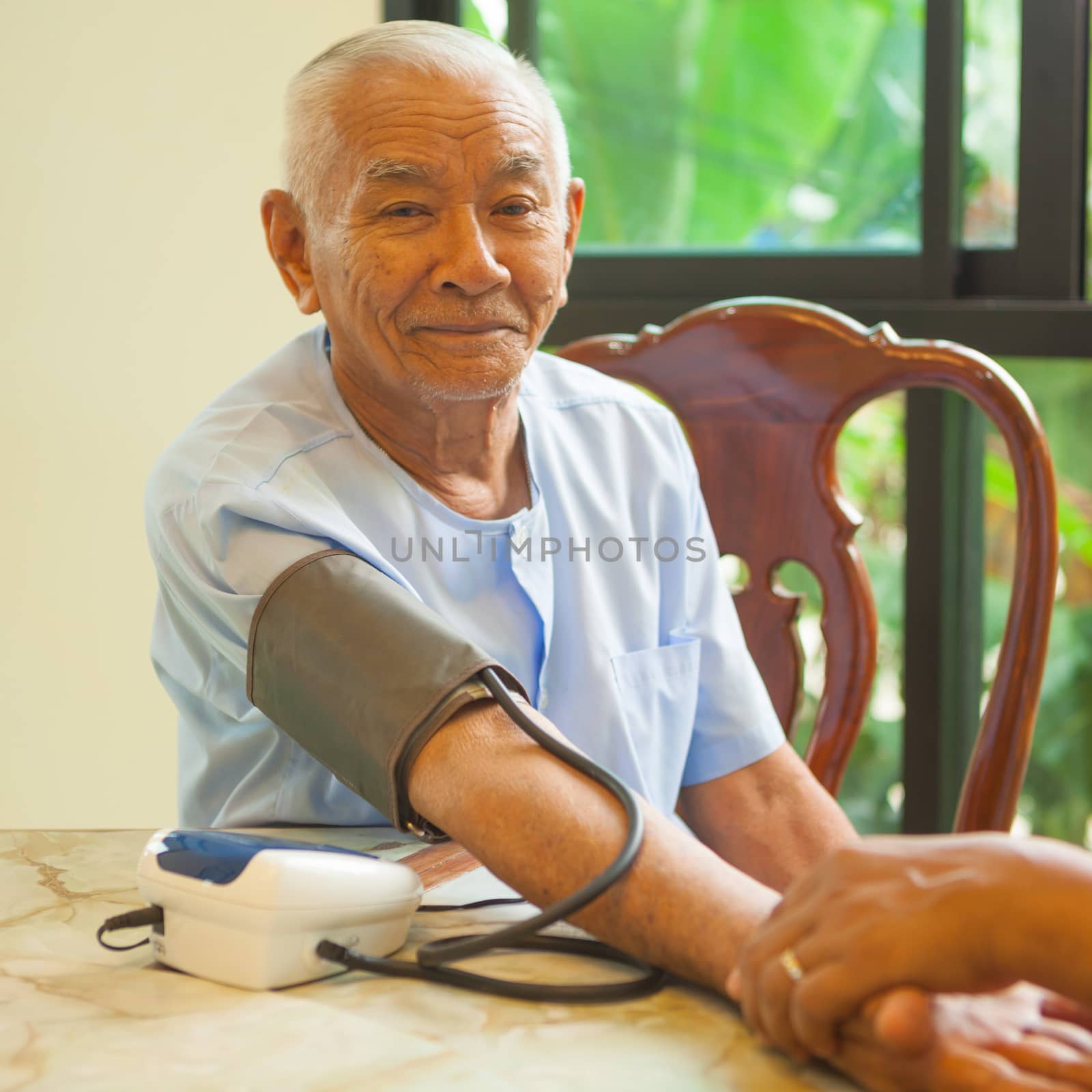 doctor measuring blood pressure of senior asian man patient