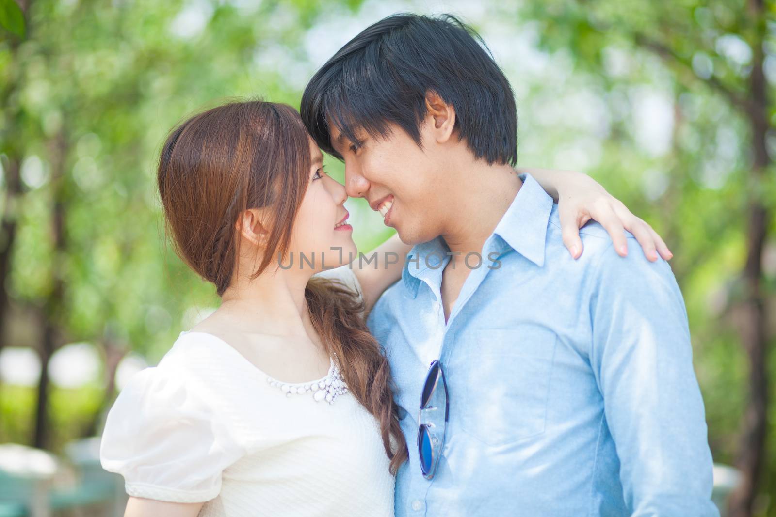 Loving asian couple under tree in the park