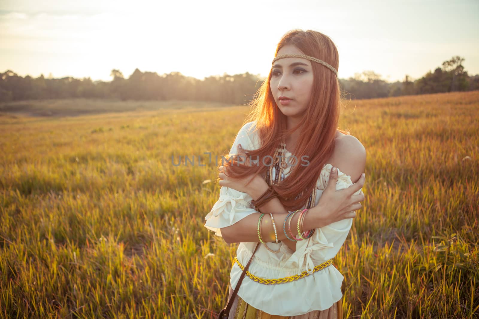 Hippie woman posing in golden field on sunset