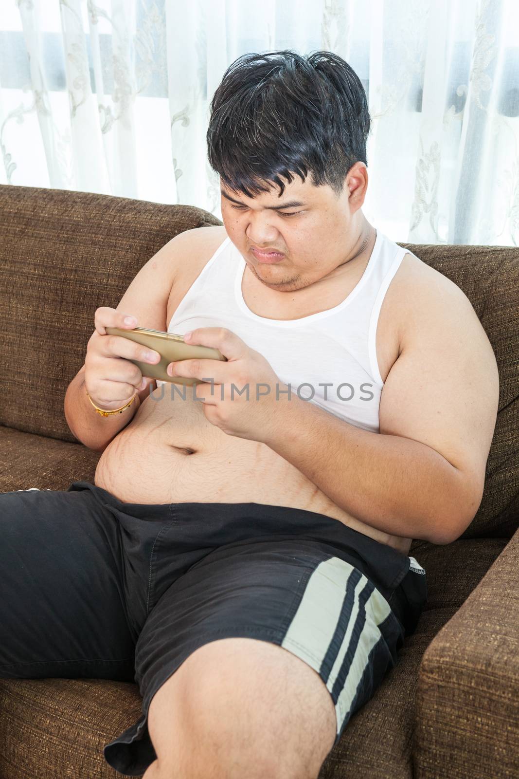 Fat asian man play game with his smartphone