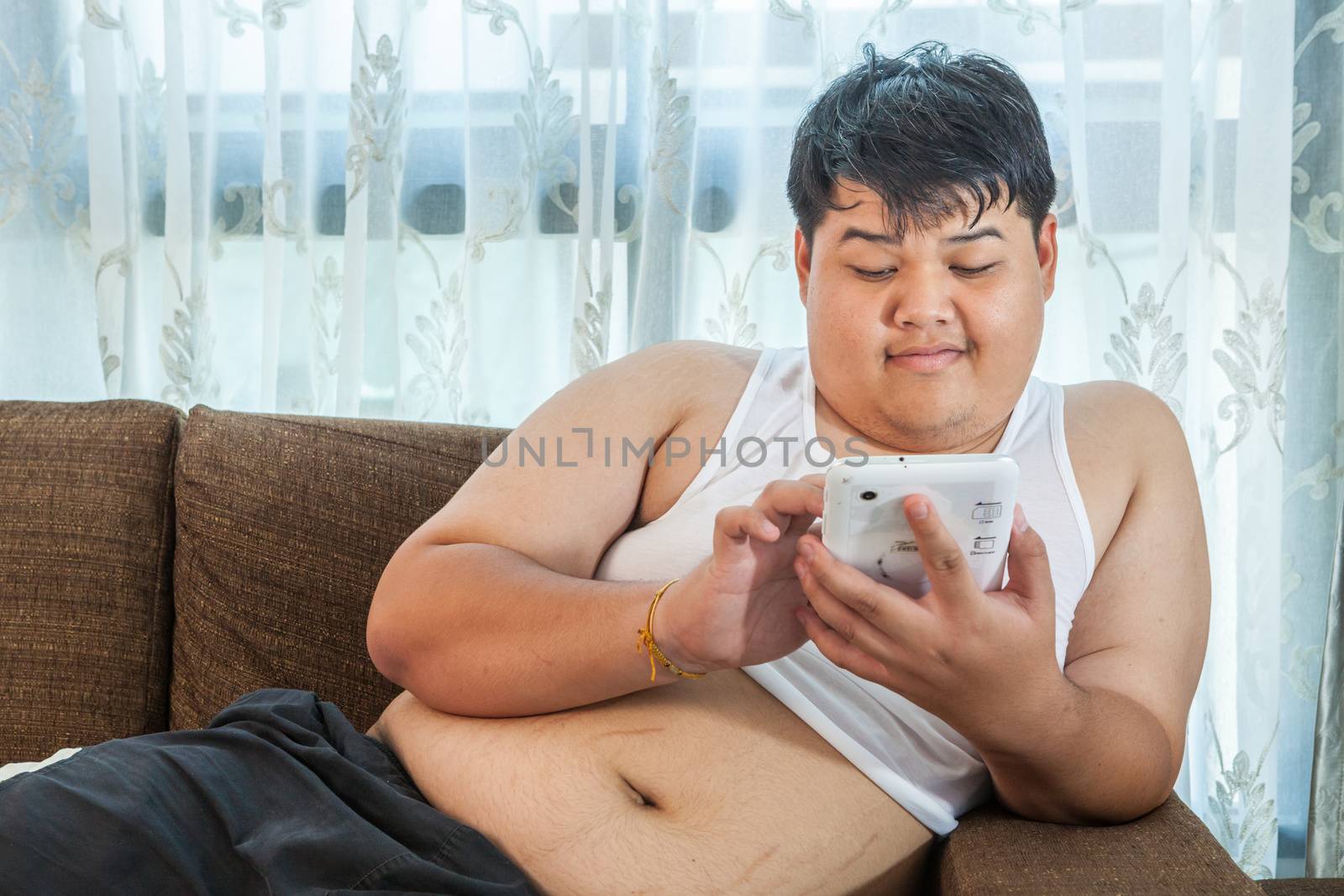 Asian fat man Relaxing in the sofa with the tablet at home