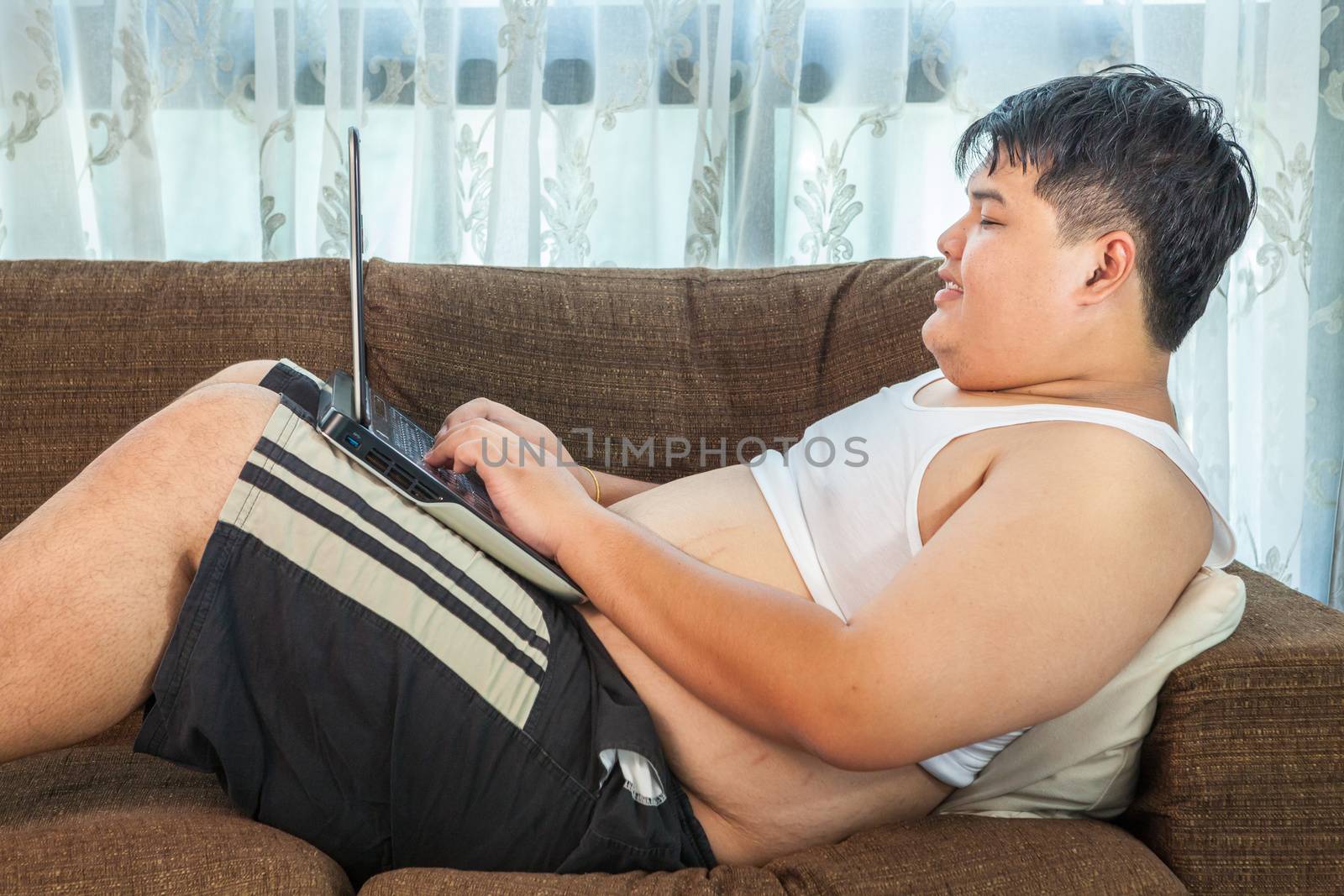 Asian fat man using laptop in home