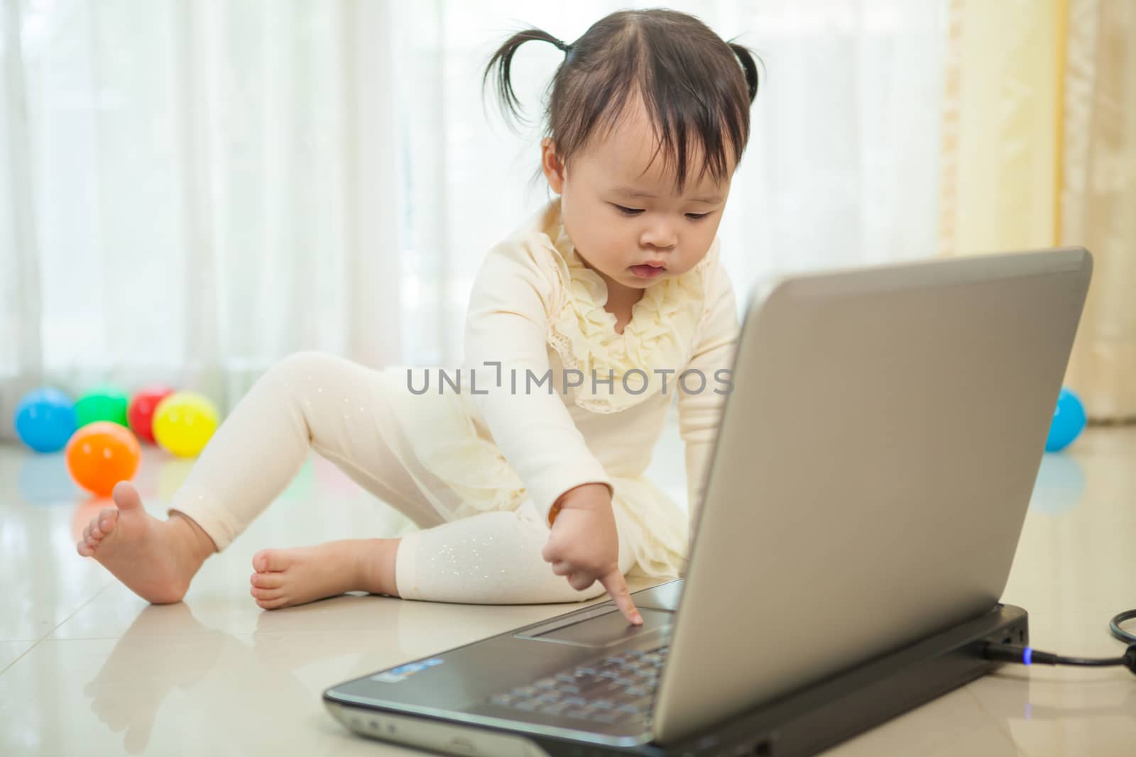 Little asian girl play laptop in home by witthaya