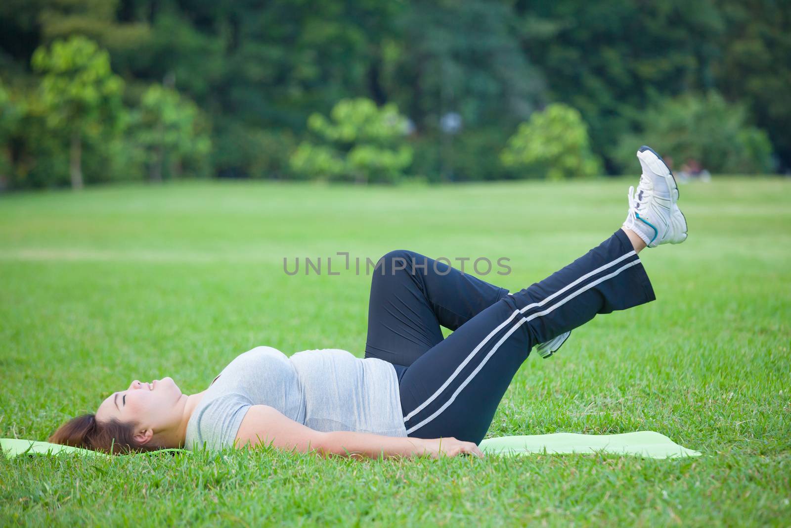 Asian fat woman lying by exercise leg upwards at the park