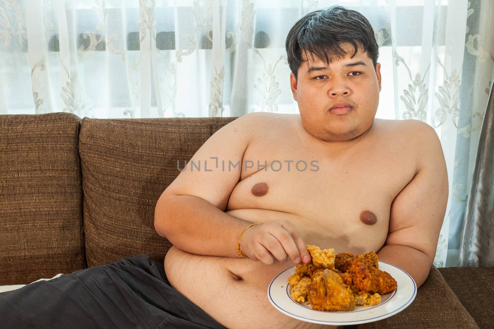 Asian fat man eating fried chicken by witthaya