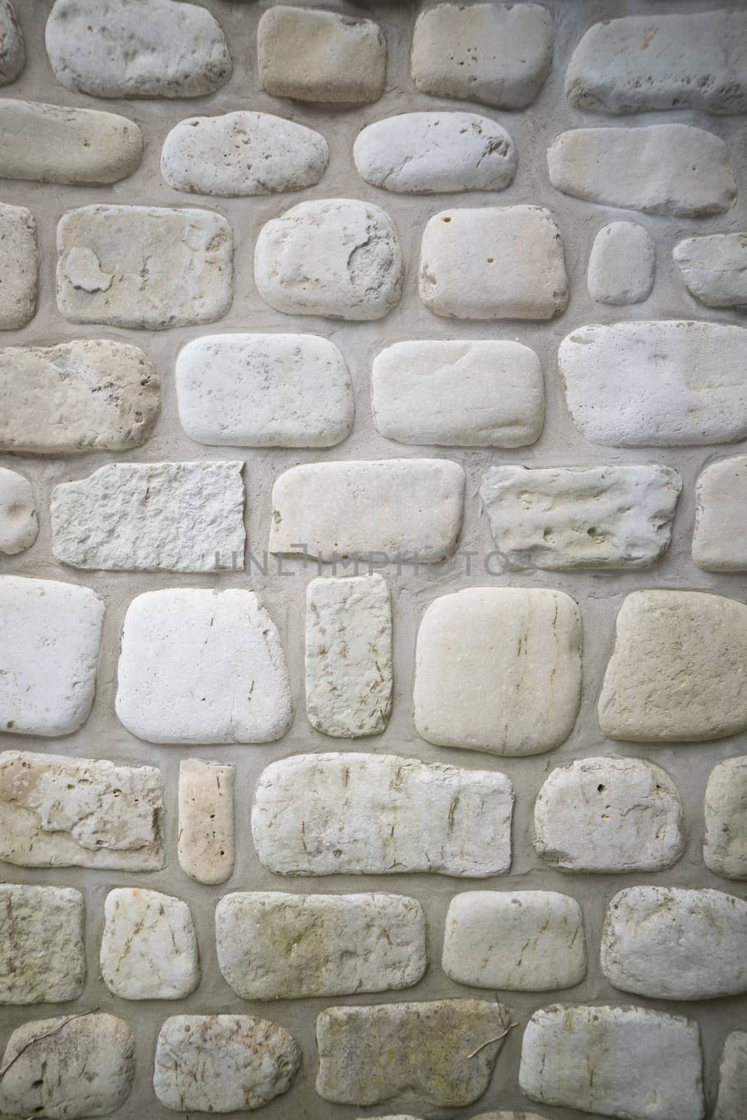 Old stone wall background with rounded limestone cobbles in the wall of a waterfront cottage on georgian bay. Has cement mortar between.