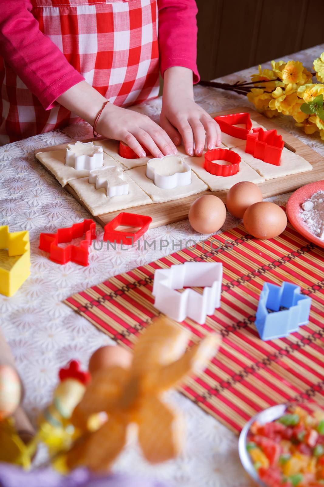 Little girl hands rolling dough at kitchen