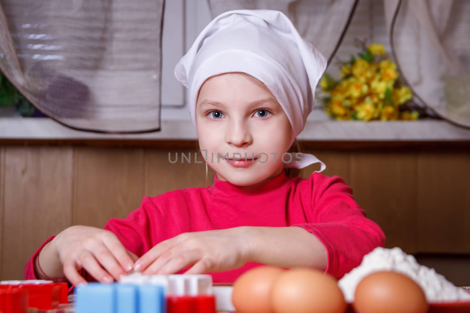 Cute girl in apron making easter cookies in kitchen