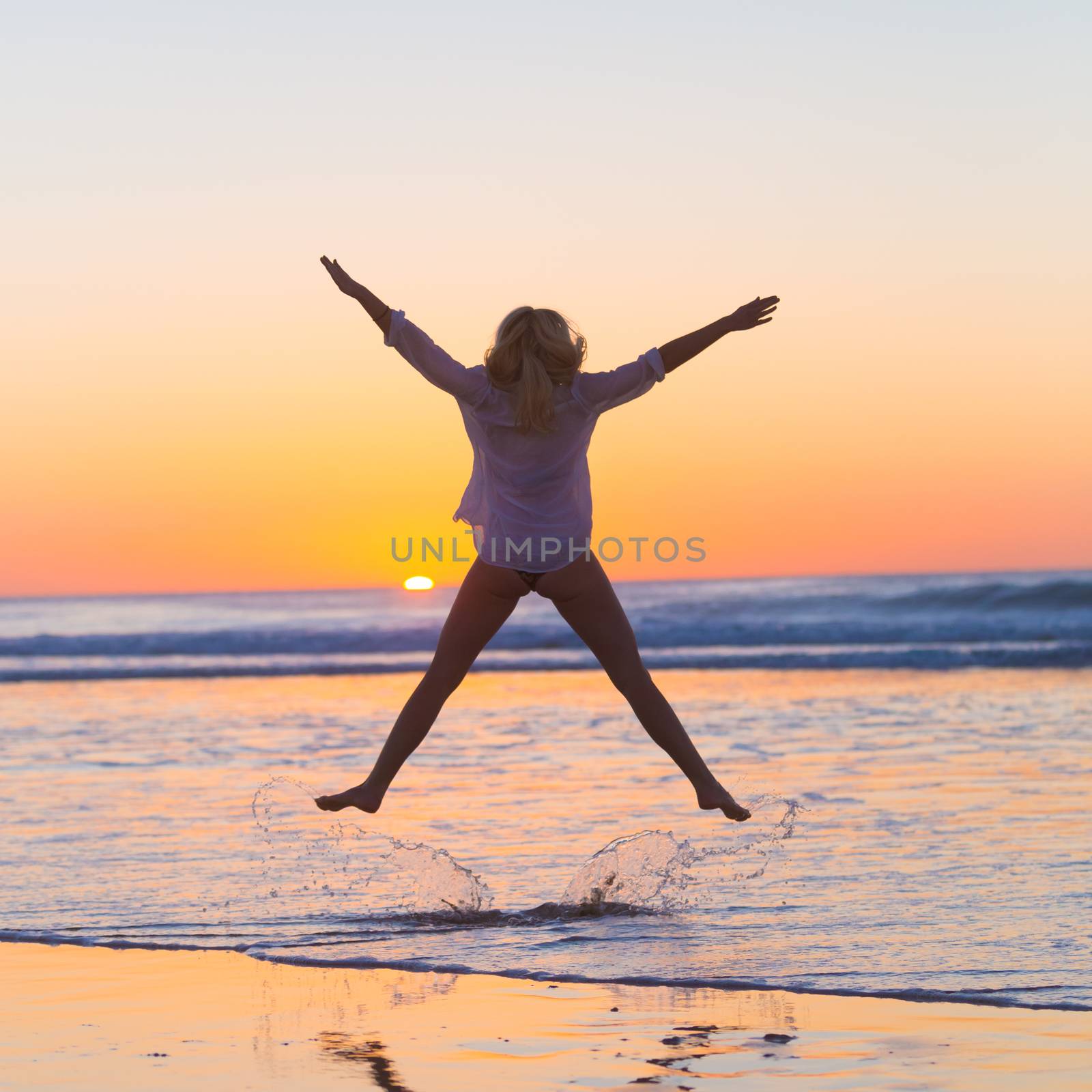 Young beautiful woman jumping in the beach. by kasto