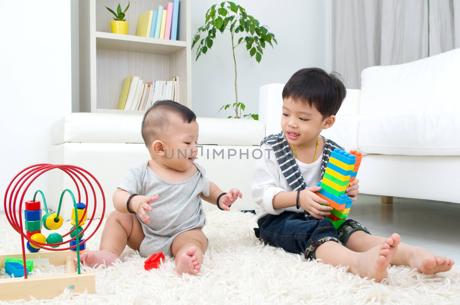 Asian kids sitting on the floor, playing with toy.