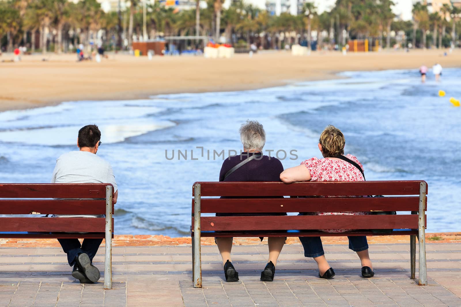 Seniors sitting and on the benches in front of the ocean or sea