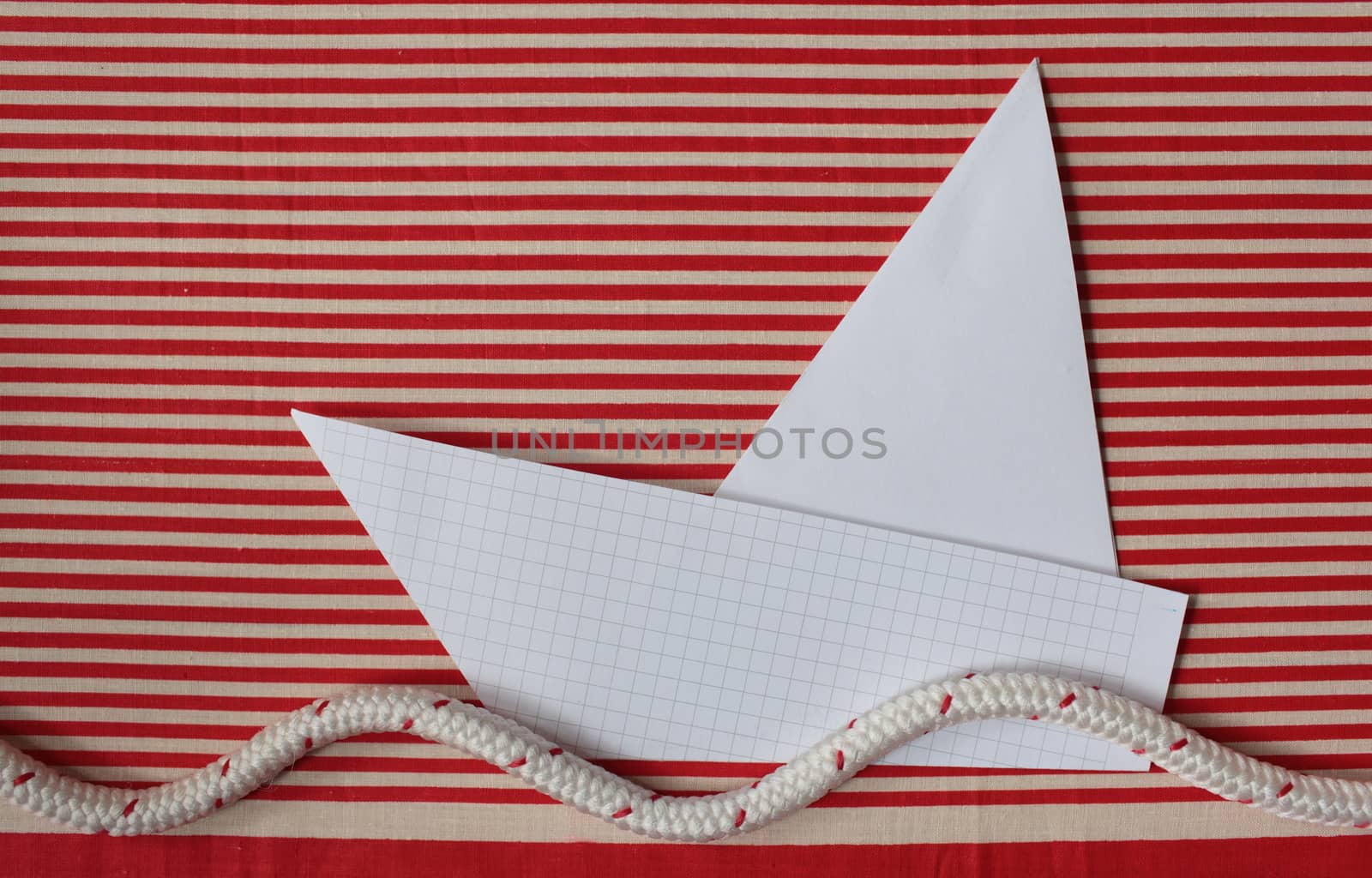 origami white paper yacht.  red striped sea. flat lay