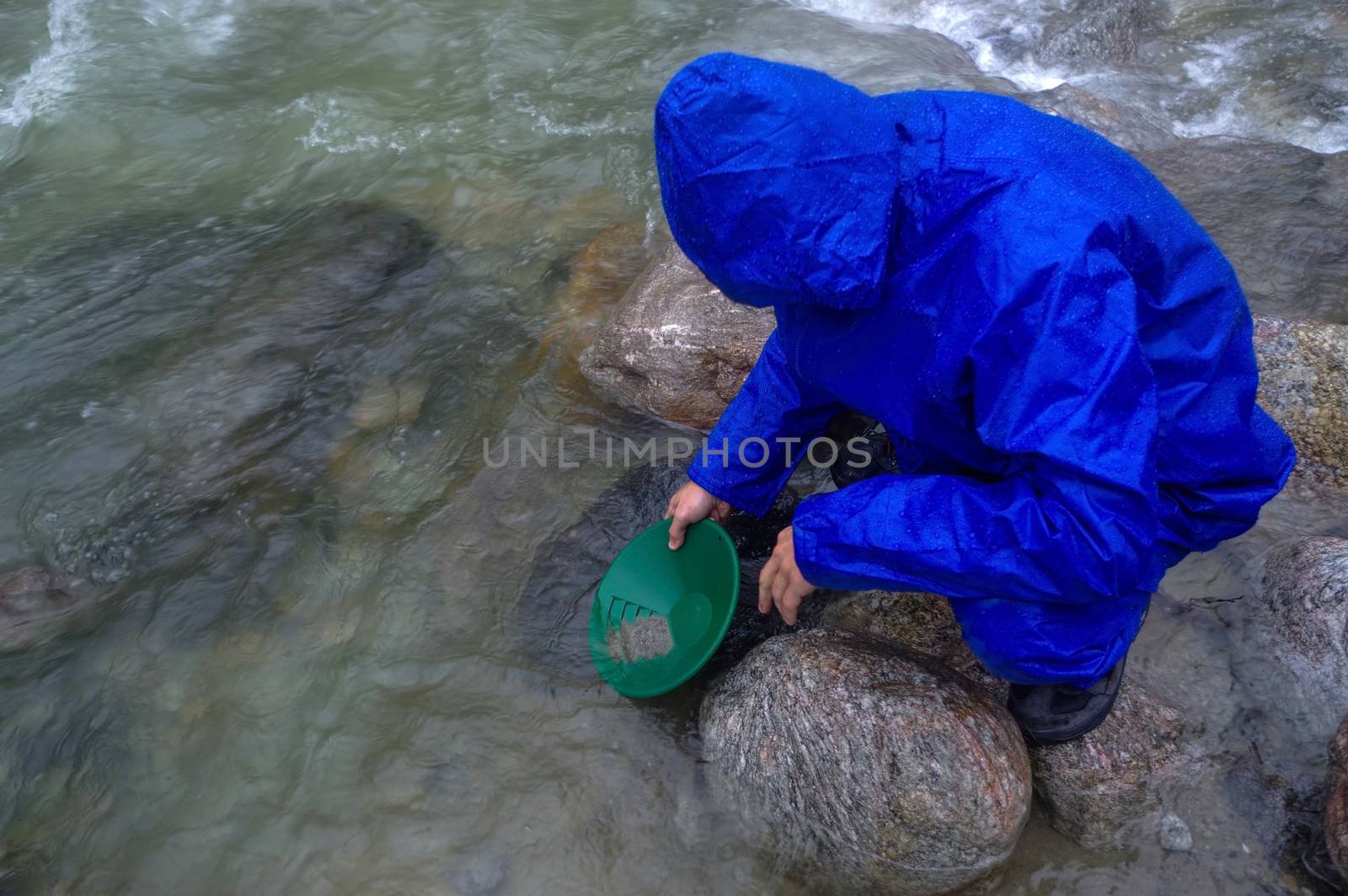 man, prospector panning gold in a river with sluice box on  rain by evolutionnow
