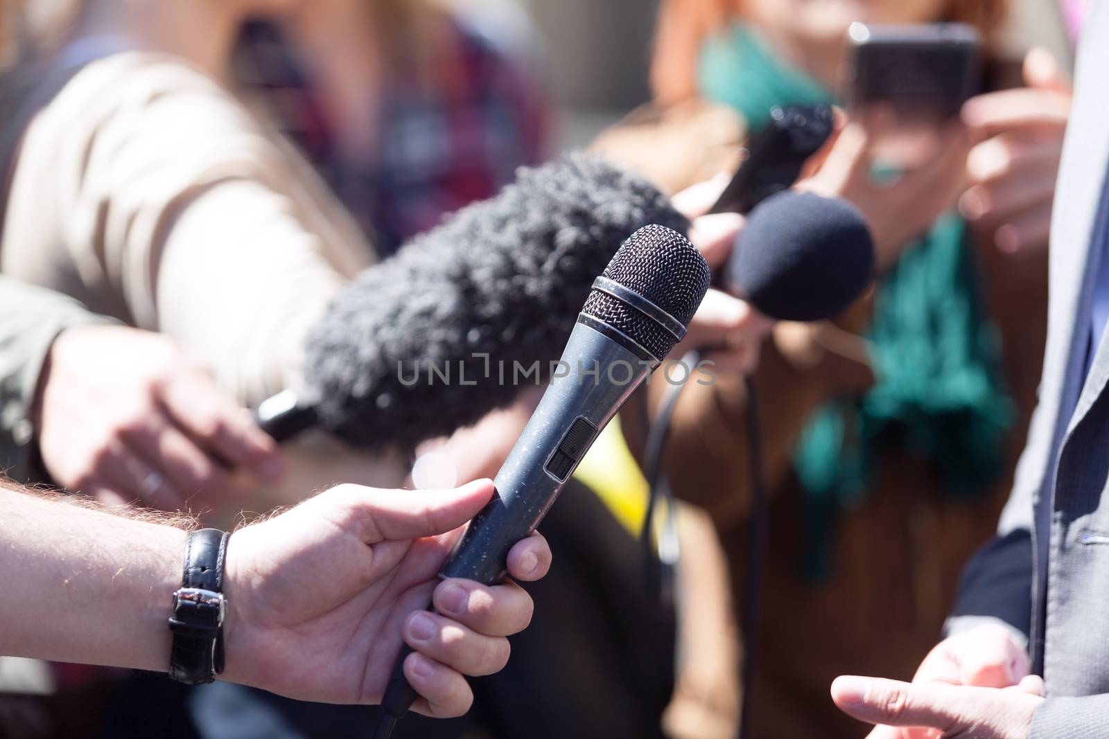 Reporters holding microphones conducting media interview