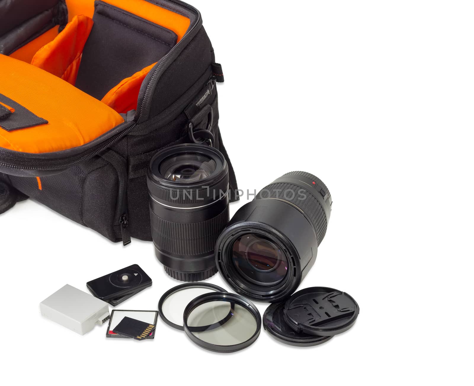 Two different photo lenses and some other photo accessories against the background of the fragment of the open camera bag on a light background
