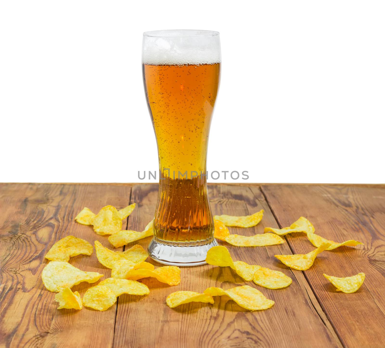 Beer glassware with the lager beer among the potato chips scattered the old wooden planks on a light background
