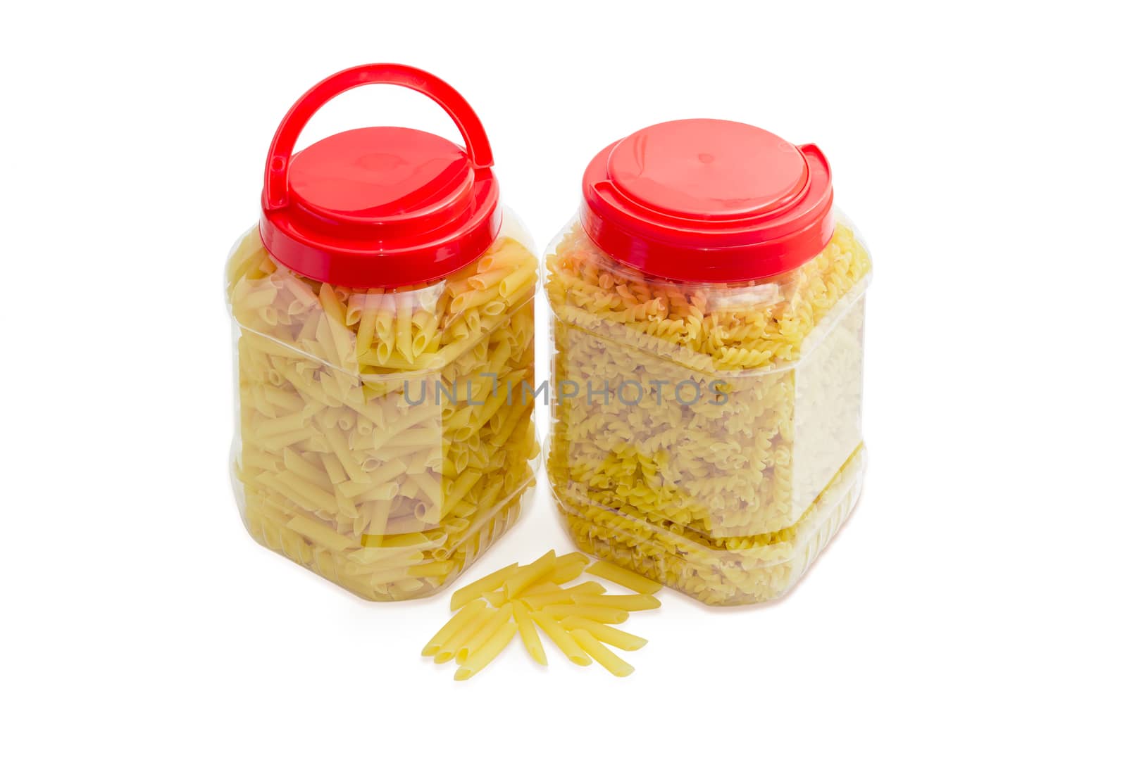 Uncooked dried spiral pasta and cylinder-shaped pasta in two transparent plastic containers with the red covers on a light background
