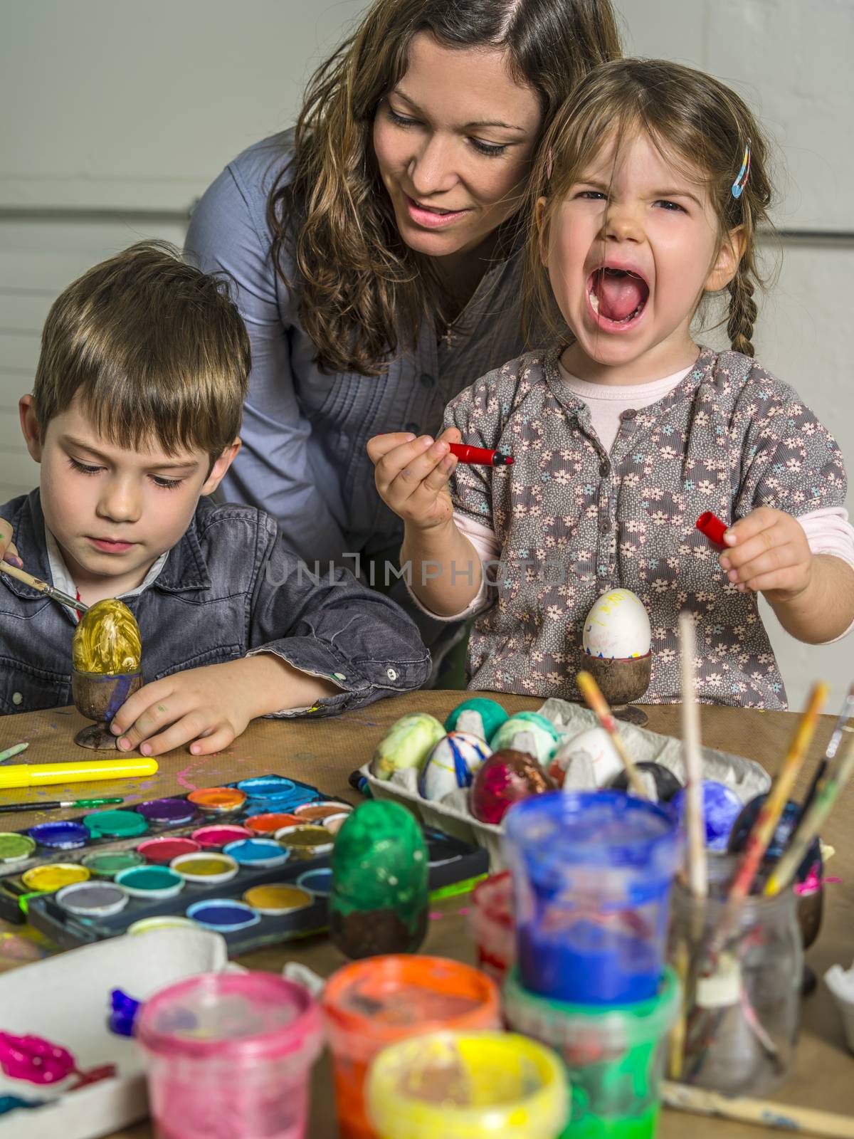 Photo of a mother and her children painting and decorating hard-boiled eggs for easter.
