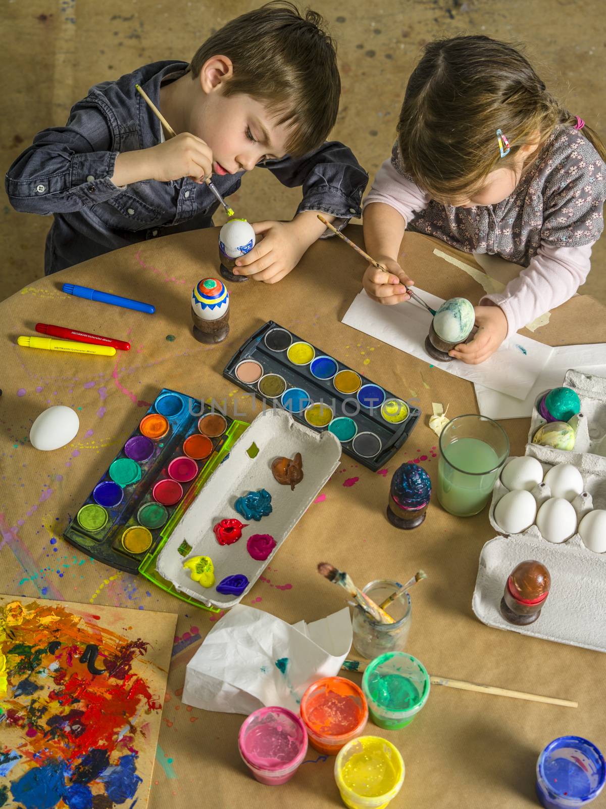 Photo of a brother and sister painting and decorating hard-boiled eggs for easter.