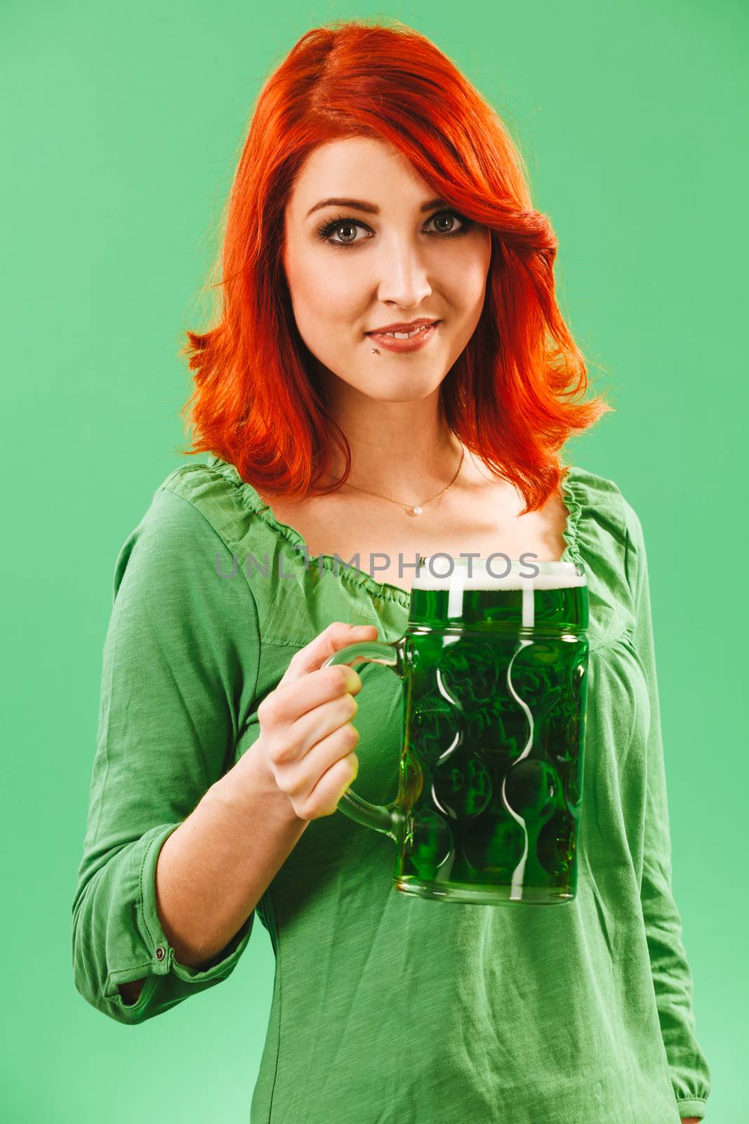 Photo of a beautiful redhead woman holding and drinking a huge green beer.
