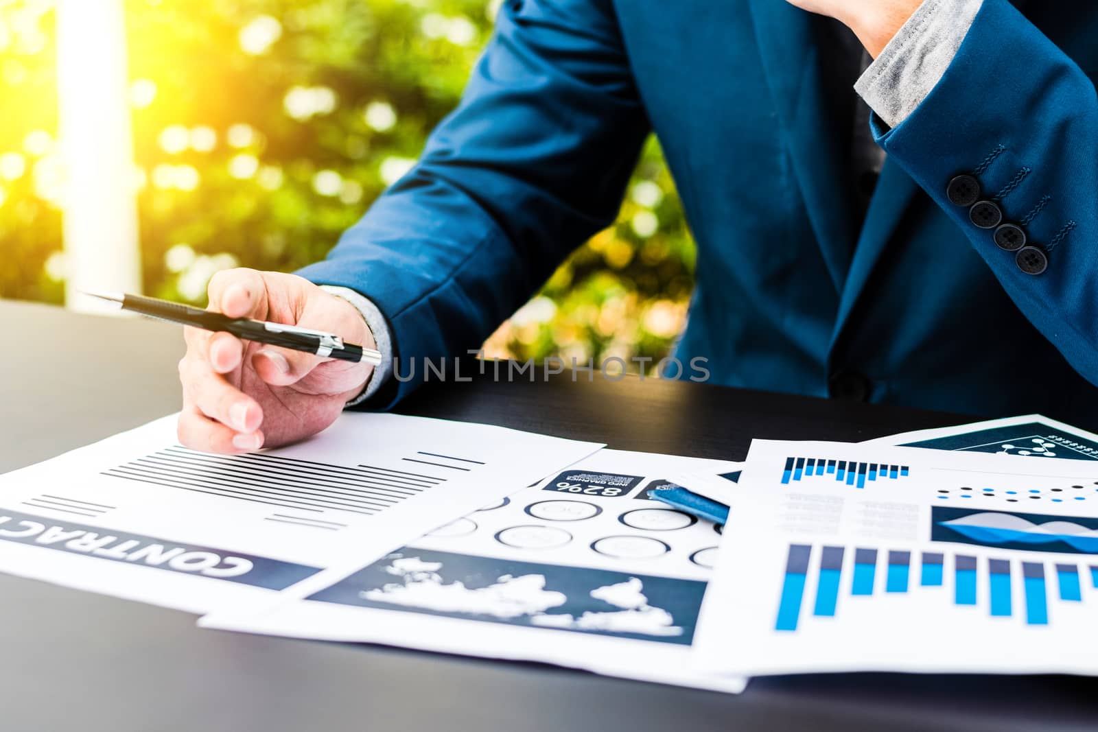 Handsome businessman wearing suit and using modern laptop outdoors and graph finance diagram,