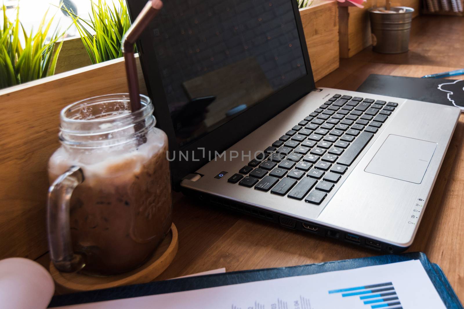 Coffee cup  on a table with laptob and graph finance diagram in coffee shop.