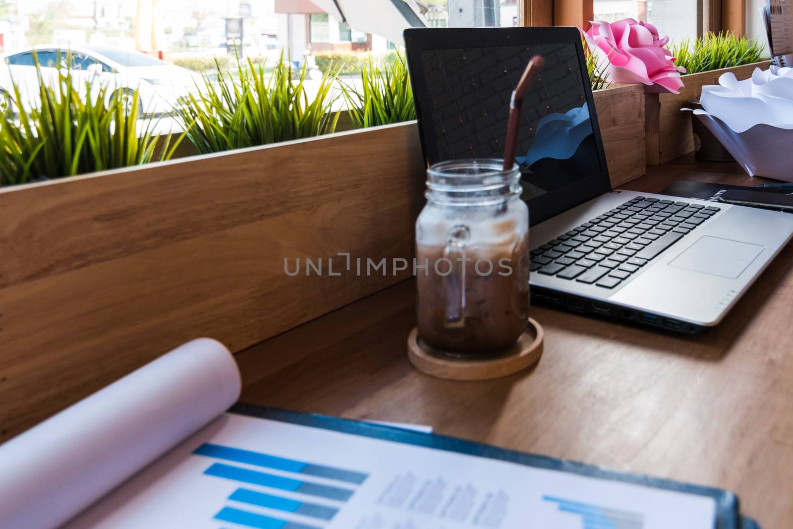 Coffee cup  on a table with laptob and graph finance diagram in coffee shop.