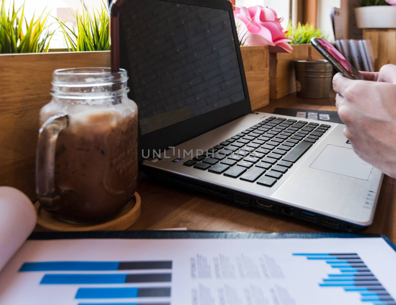 Coffee cup  on a table with laptob and graph finance diagram in coffee shop.