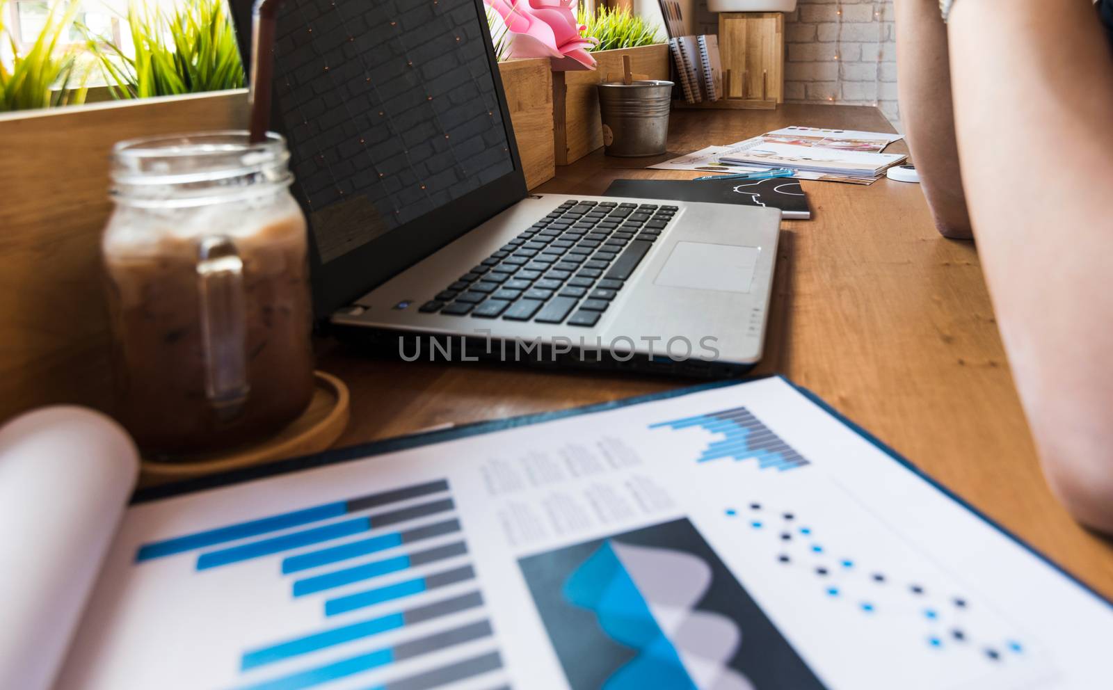 Coffee cup  on a table with laptob and graph finance diagram in coffee shop.