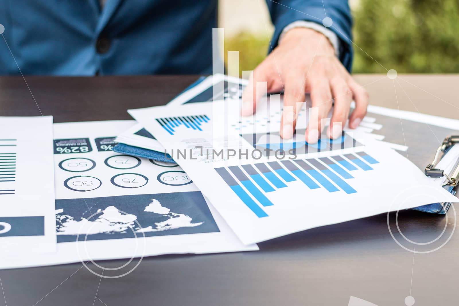 Handsome businessman wearing suit and using modern laptop outdoors and graph finance diagram.