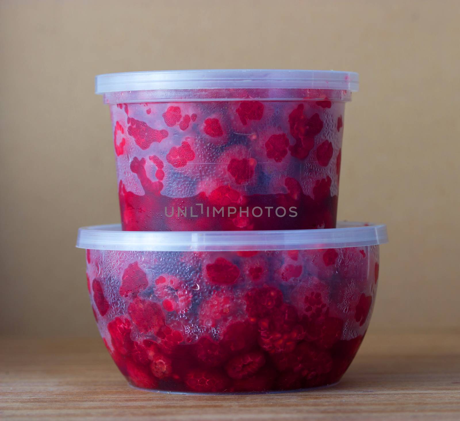 Raspberry in the round box with leaf of mint on the old wood background