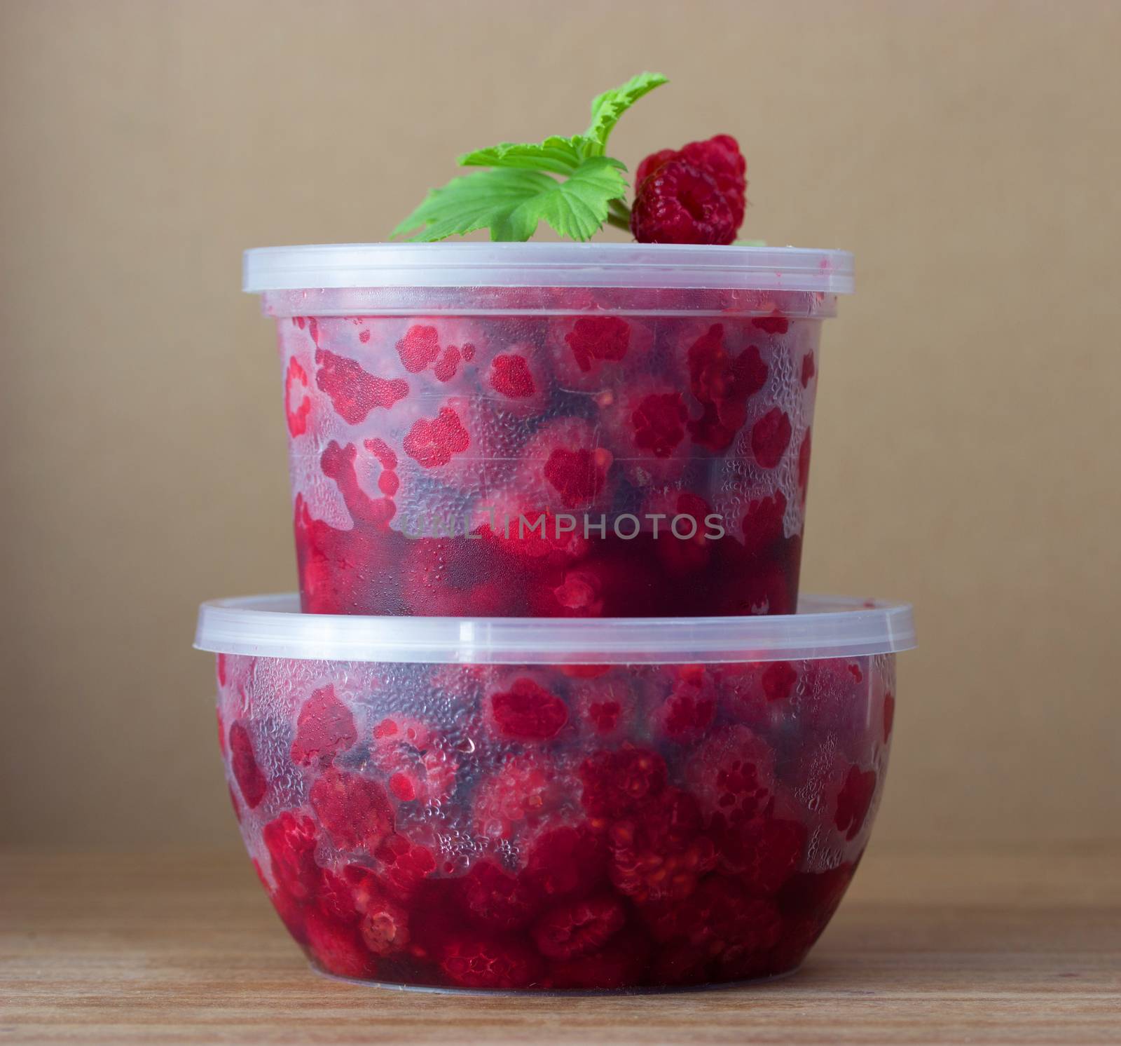 Raspberry in the round box with leaf of mint on the old wood background