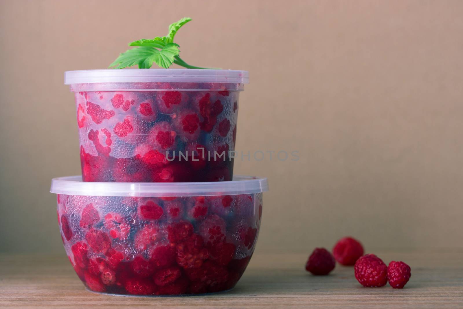 Raspberry in the round box with leaf of mint on the old wood background