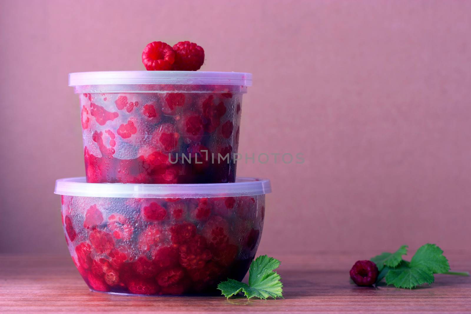 Raspberry in the round box with leaf of mint on the old wood background