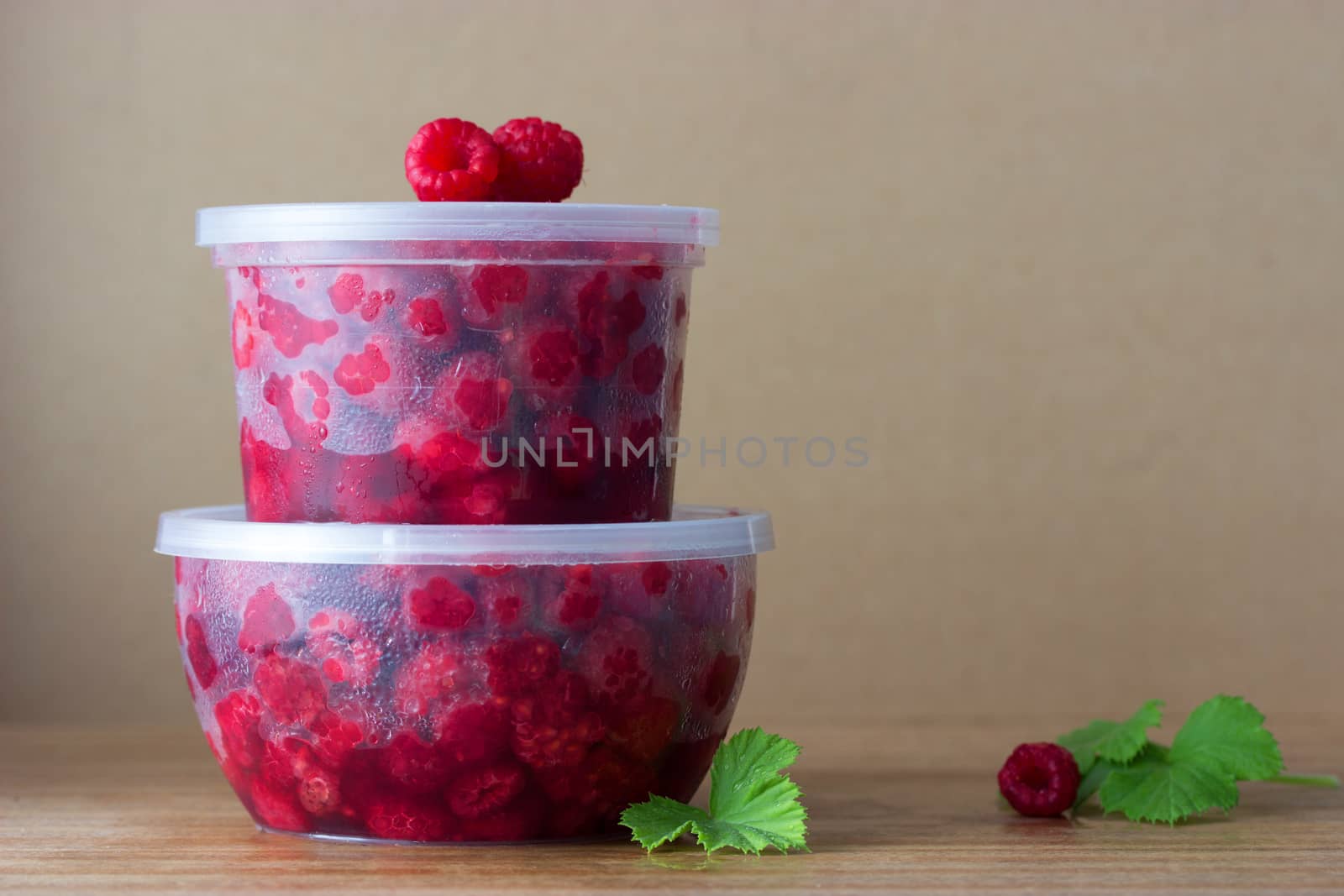 Raspberry in the round box with leaf of mint on the old wood background