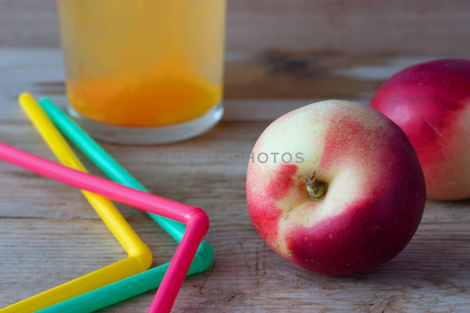 Ripe peaches and glass of juice on wooden background